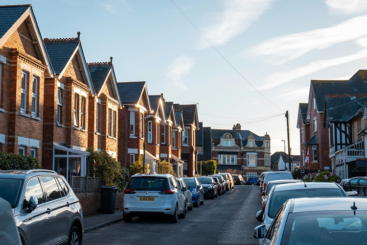 Cars parked along a street of brick terraced houses in the UK