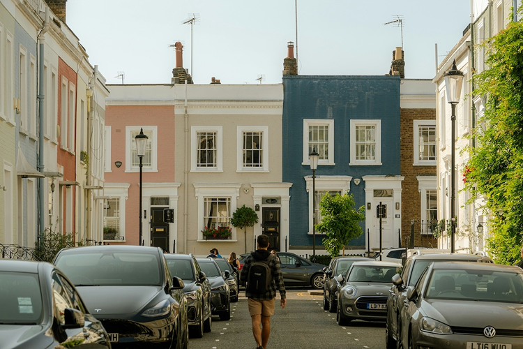 Cars parked along a street of colourful terraced houses in the UK