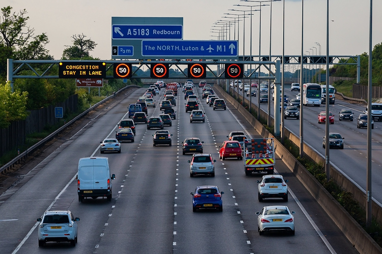 Heavy traffic on a UK motorway with overhead speed limit signs