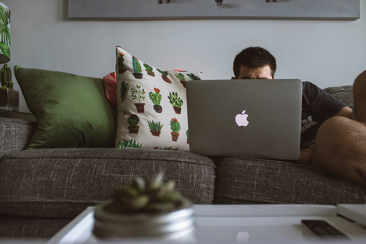 Man relaxing on sofa with laptop
